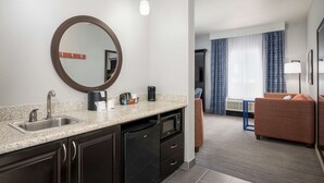 Un baño de hotel moderno con lavamanos, espejo y cafetera.