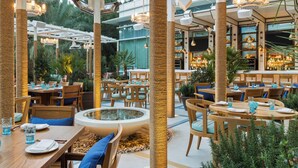 Een terras met ronde tafels, stoelen en een fontein.