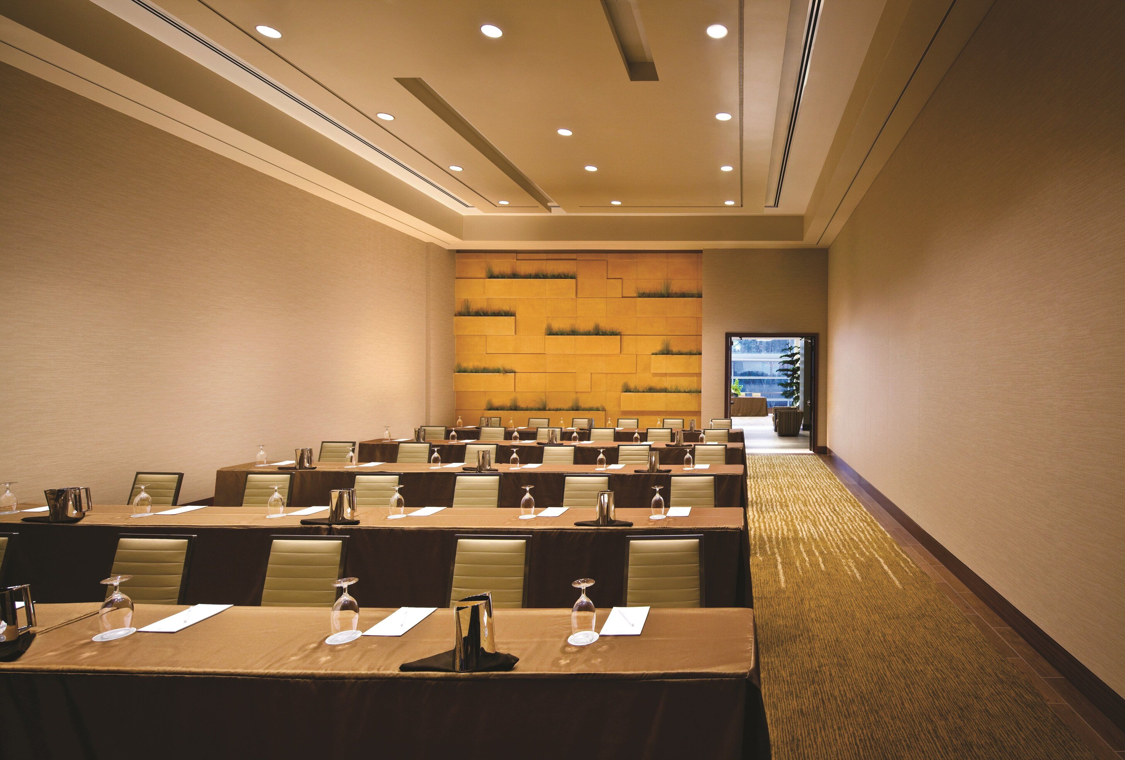 A conference room with multiple tables, chairs, and a decorative wall.