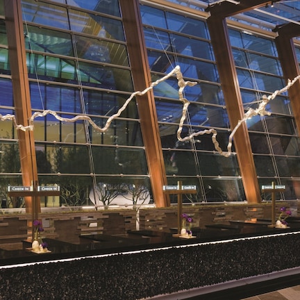 A reception area with a glass wall, wooden reception desk, and multiple 'Check In' signs.