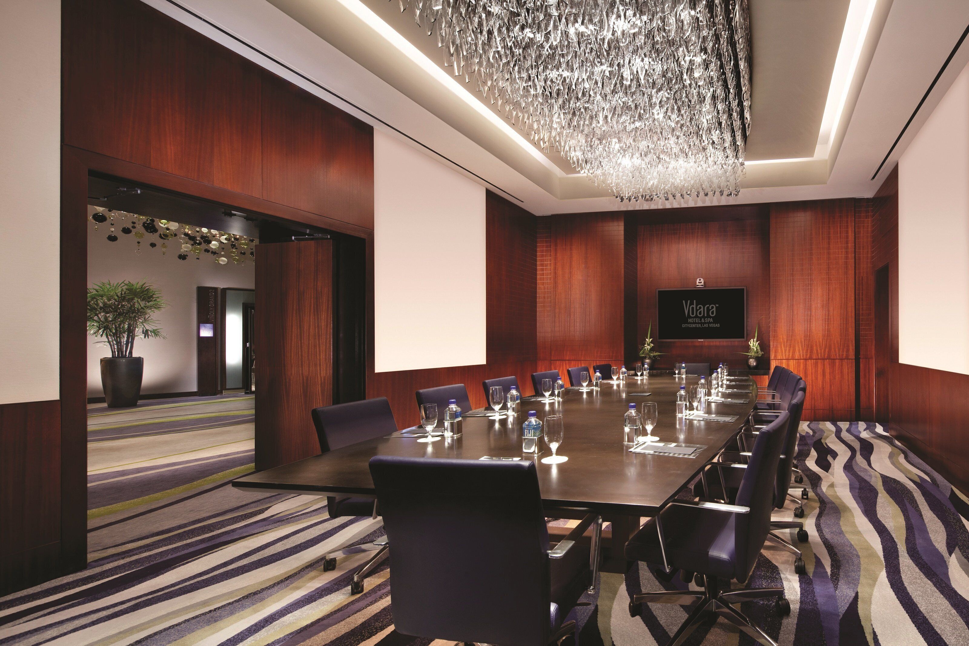 A conference room with a long table, chairs, and a projector screen.