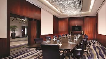 A conference room with a long table, chairs, and a projector screen.
