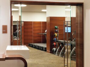 A fitness center with exercise equipment, a treadmill, and a wall-mounted rack of weights.