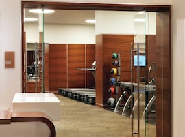 A fitness center with exercise equipment, a treadmill, and a wall-mounted rack of weights.