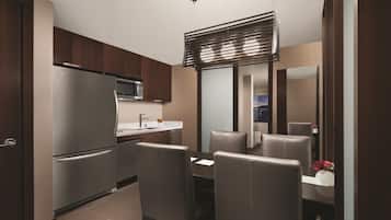 A modern kitchen with a refrigerator, microwave, and dining area with chairs and a table.