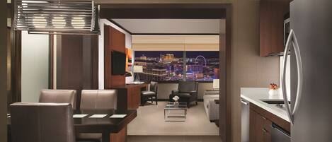 A modern kitchen with a city view, a dining area with leather chairs, and a living space with a sofa and coffee table.