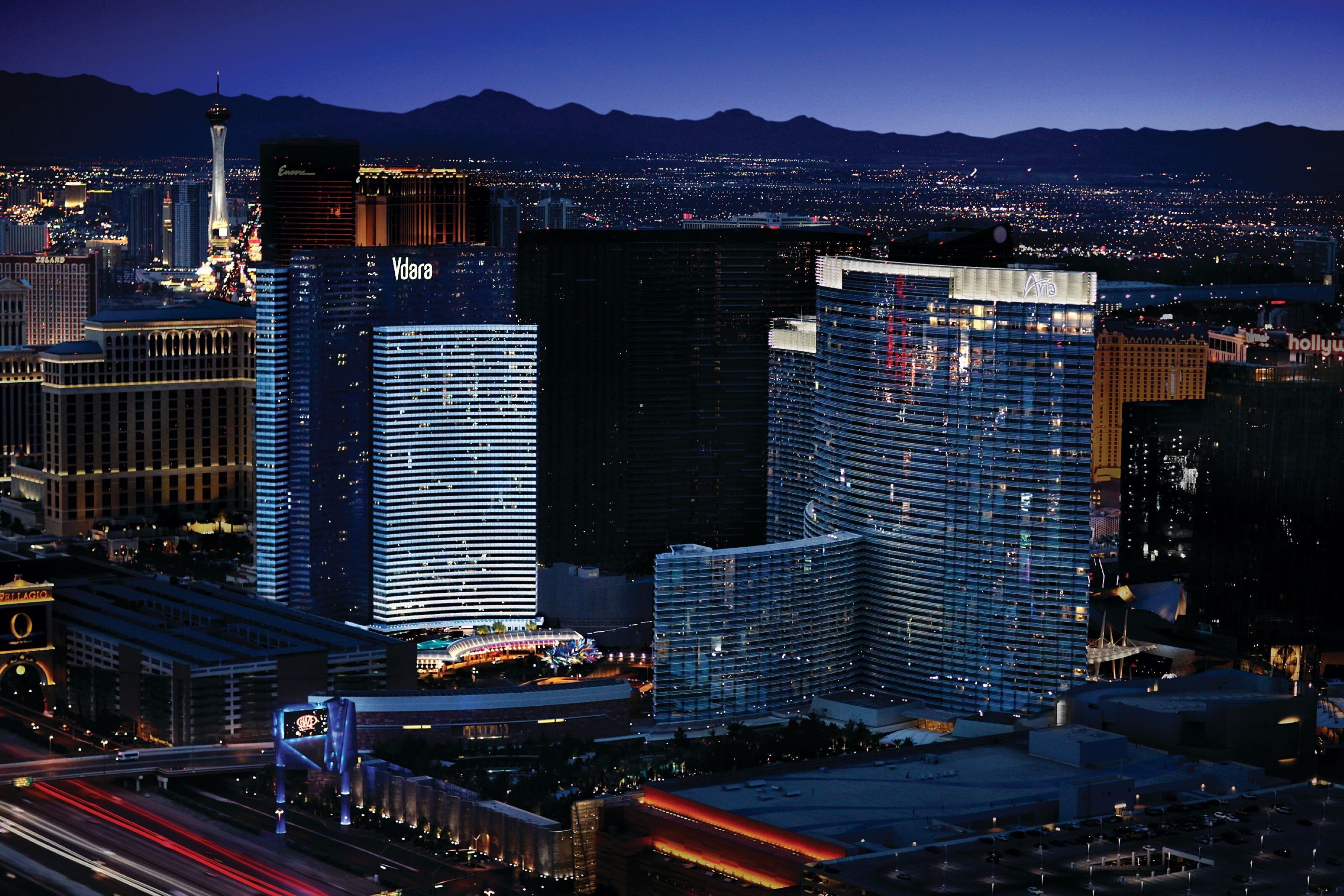 A cityscape with prominent buildings including a tall tower and several high-rise hotels with illuminated signage.