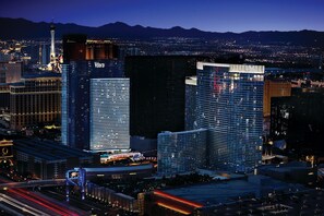 A cityscape with prominent buildings including a tall tower and several high-rise hotels with illuminated signage.