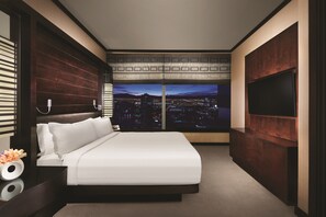 A modern bedroom with a city view, a large bed, a TV, and a wooden cabinet.
