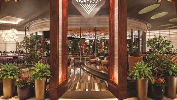 A modern lobby with a central reception desk, wooden pillars, and potted plants. - Vdara Hotel & Spa at ARIA Las Vegas (Las Vegas)