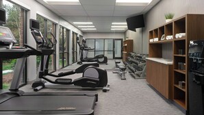 Une salle de sport équipée de tapis de course, de vélos elliptiques et de bancs de musculation.