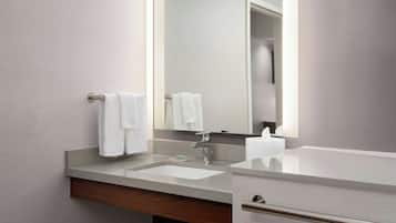 A modern bathroom with a large mirror, a sink, and a towel rack.