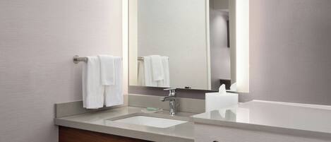 A modern bathroom with a large mirror, a sink, and a towel rack.