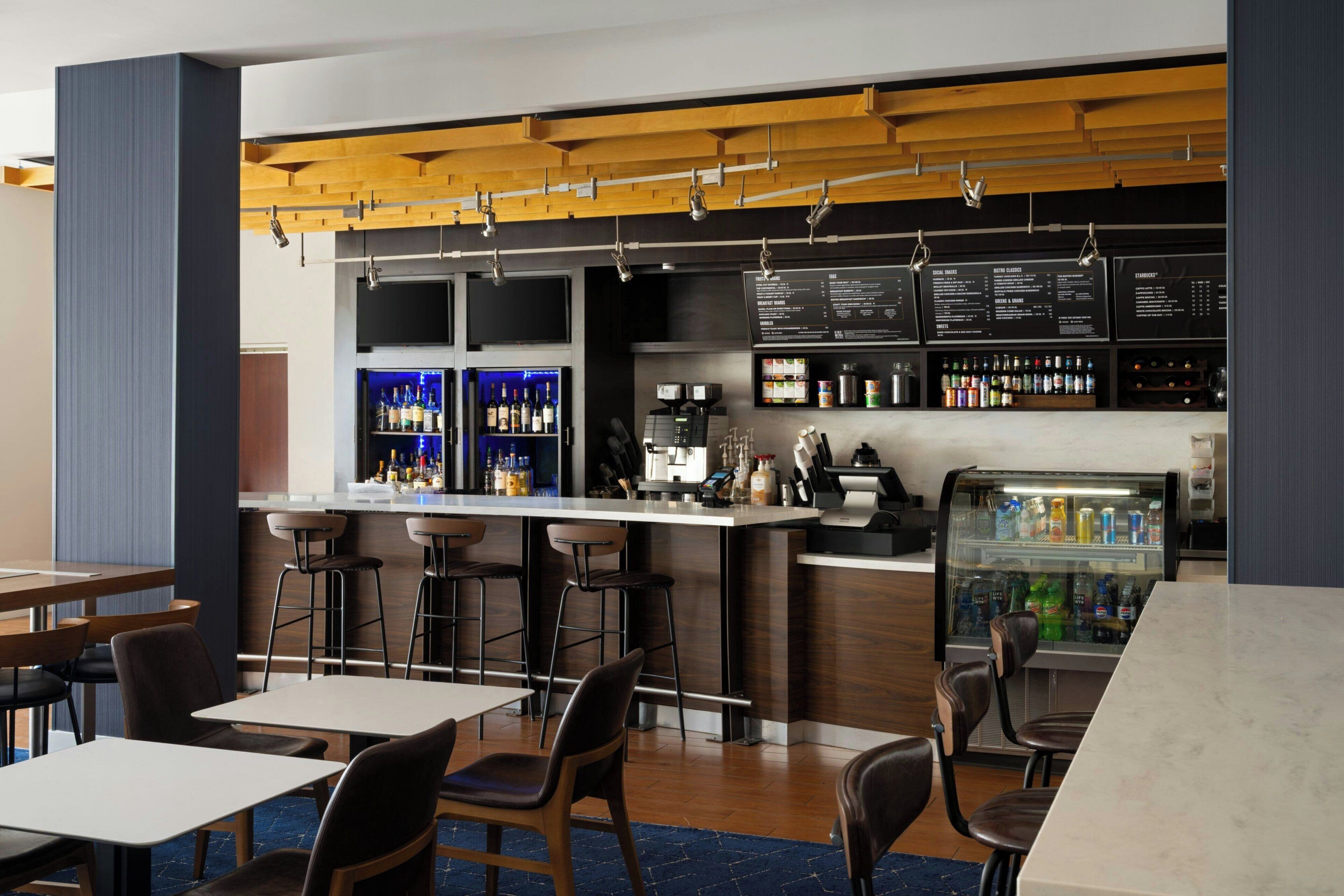 A bar area with stools, a counter, and a refrigerated display.