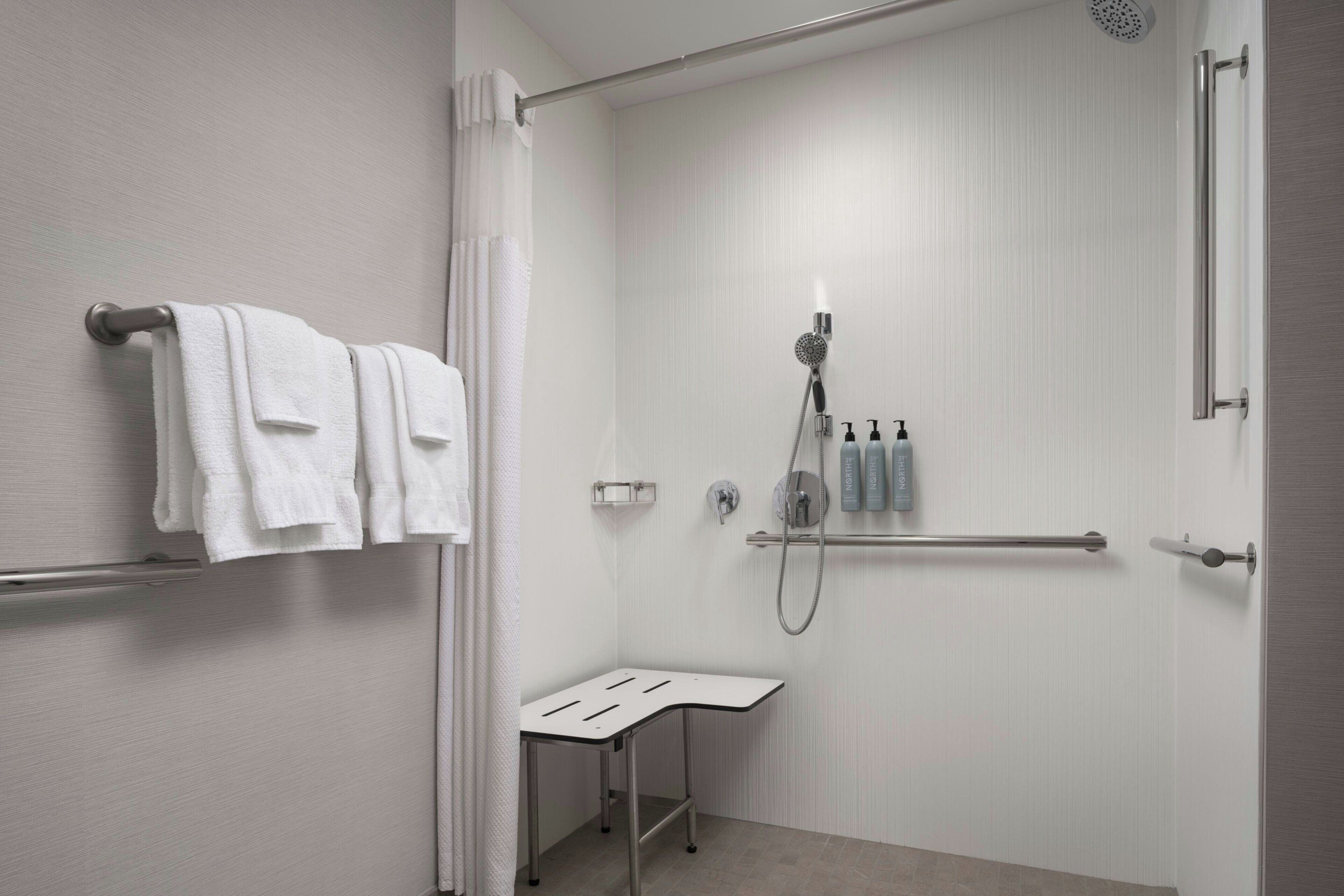 A modern bathroom with a shower, a towel rack, and a small table.