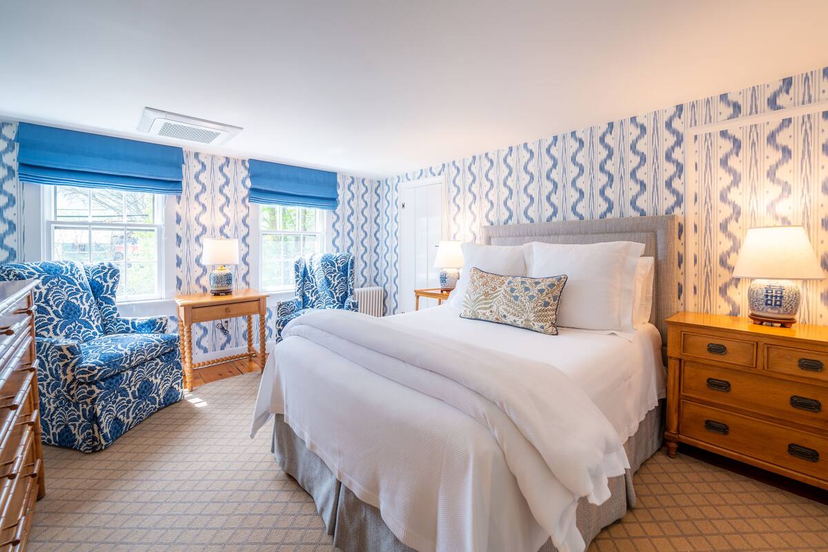A bedroom with a large bed, two bedside tables, a chair, and a dresser.