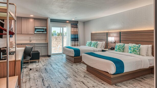 Une chambre d’hôtel moderne avec deux lits, une kitchenette et une vue sur l’extérieur.