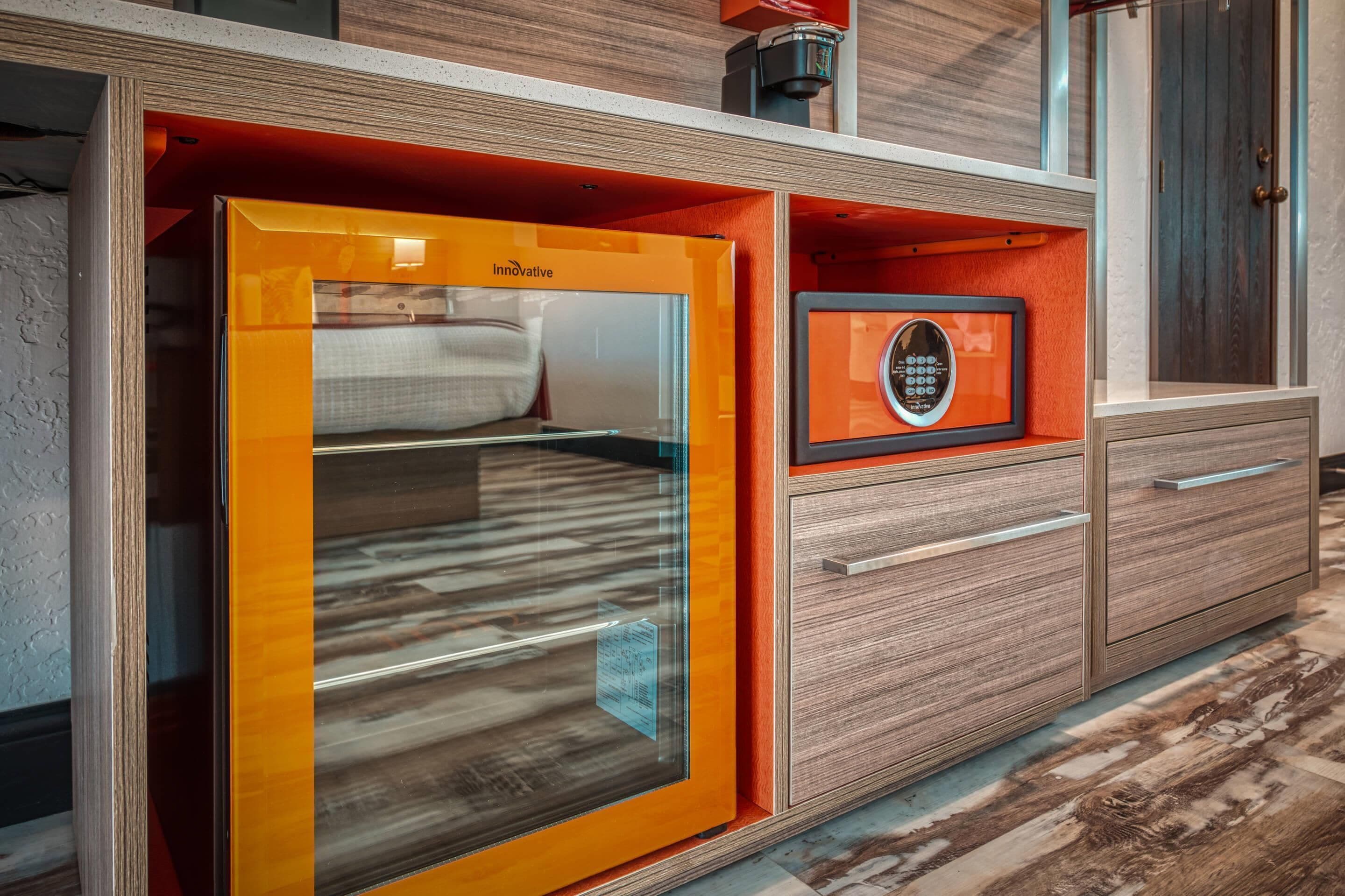 Un baño moderno con cabina de ducha de vidrio, tocador de madera con cajones y un certificado enmarcado en la pared.