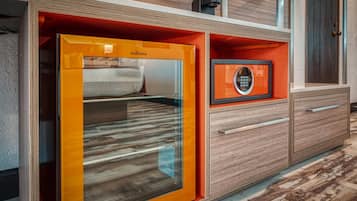 Un baño moderno con cabina de ducha de vidrio, tocador de madera con cajones y un certificado enmarcado en la pared.