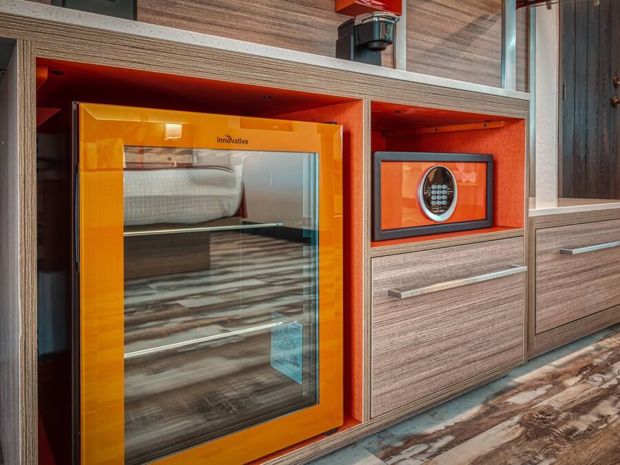 Un baño moderno con cabina de ducha de vidrio, tocador de madera con cajones y un certificado enmarcado en la pared.