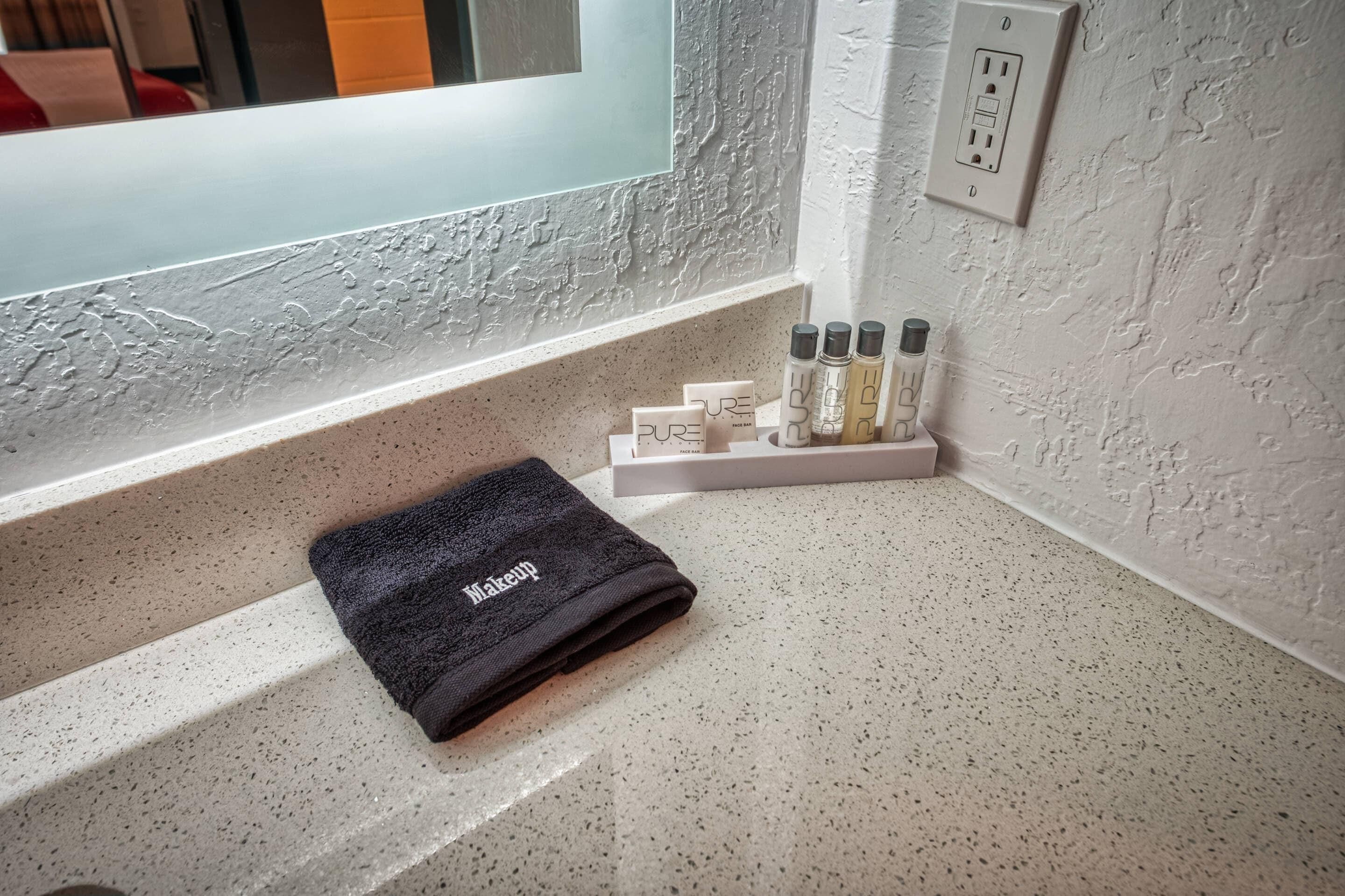 A bathroom with a towel, toiletries, and a mirror.