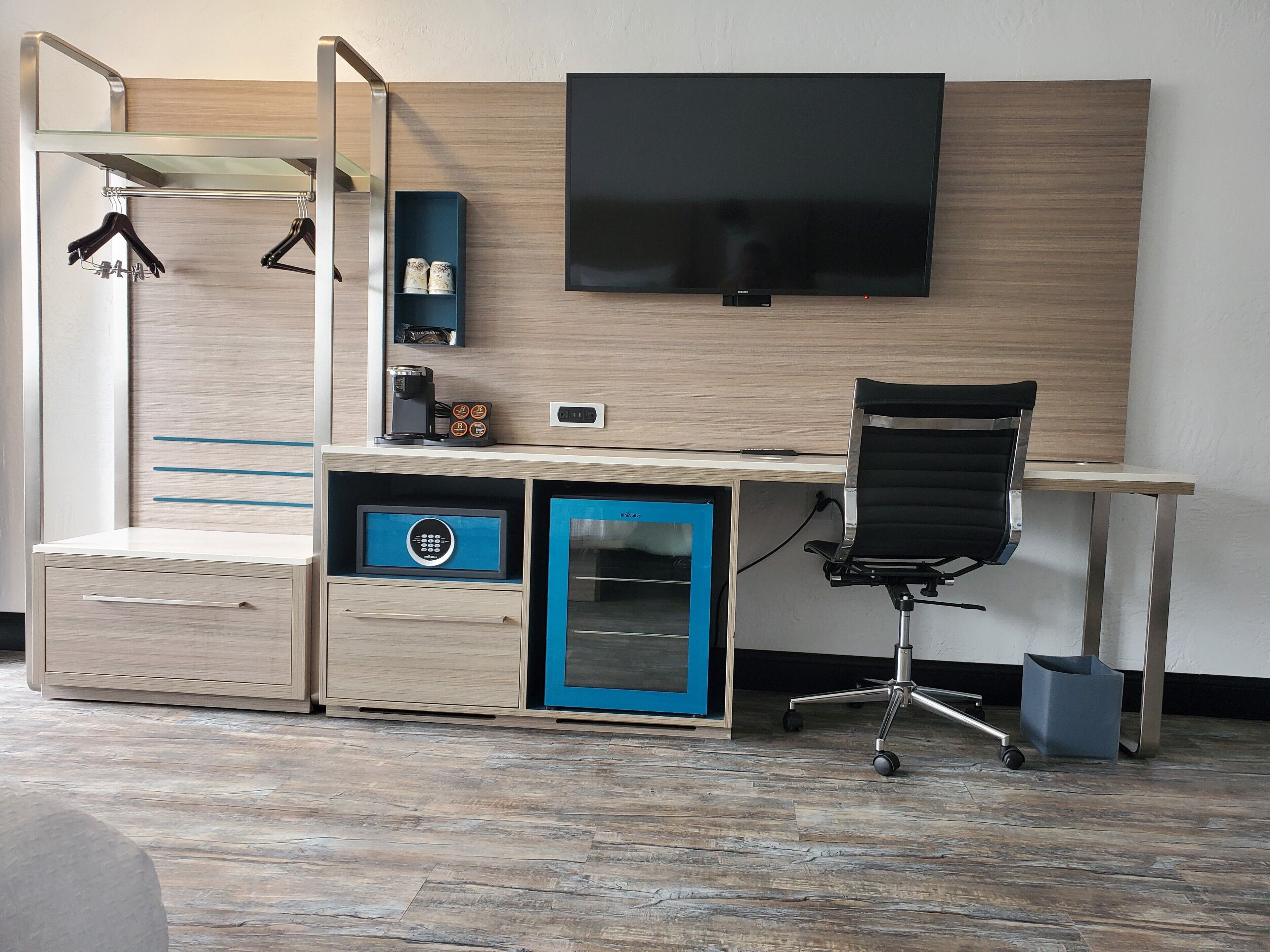 A modern bedroom with a bed, a desk, a chair, a TV, and a wardrobe.