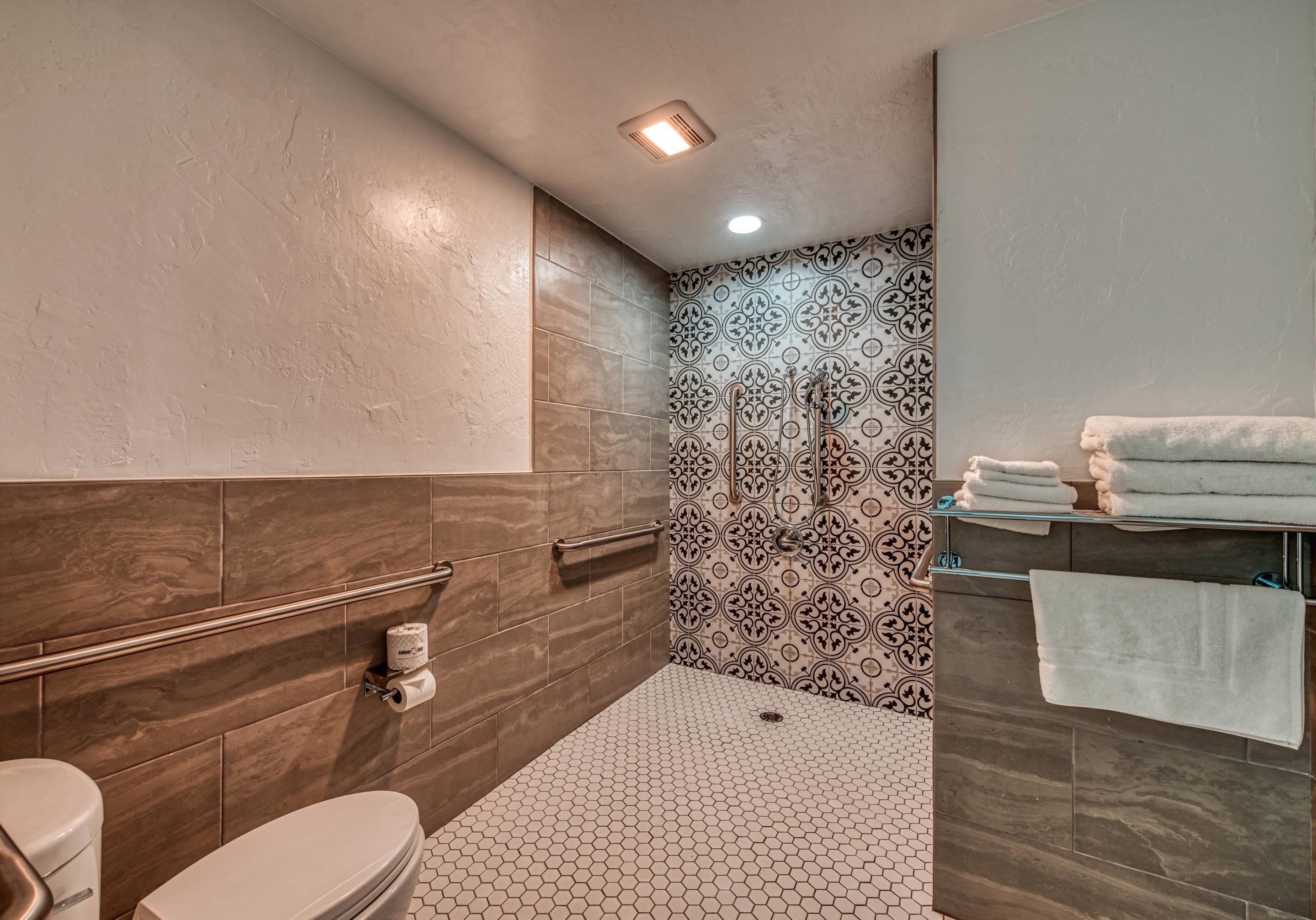 Une salle de bain moderne comprenant des toilettes, une douche et un espace lavabo.