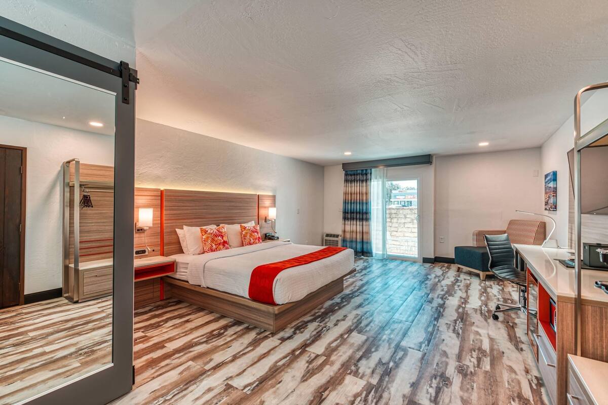 Une chambre d’hôtel moderne, dotée d’un grand lit, d’un bureau et offrant une vue sur la ville par la fenêtre.