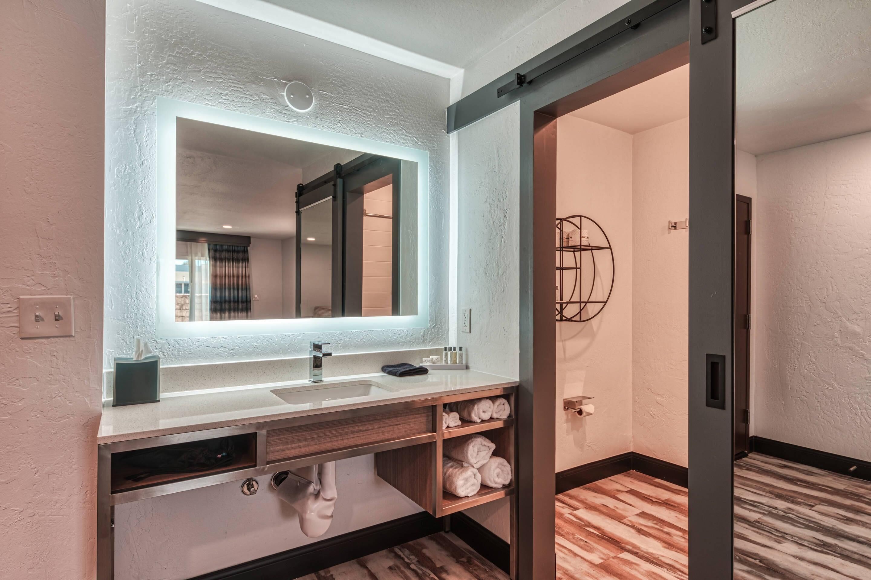 A modern bathroom with a large mirror, dual sinks, and a towel rack.