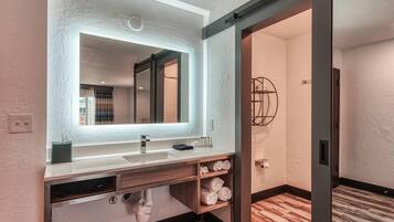 Une salle de bain moderne avec un grand miroir, deux vasques et un porte-serviettes.