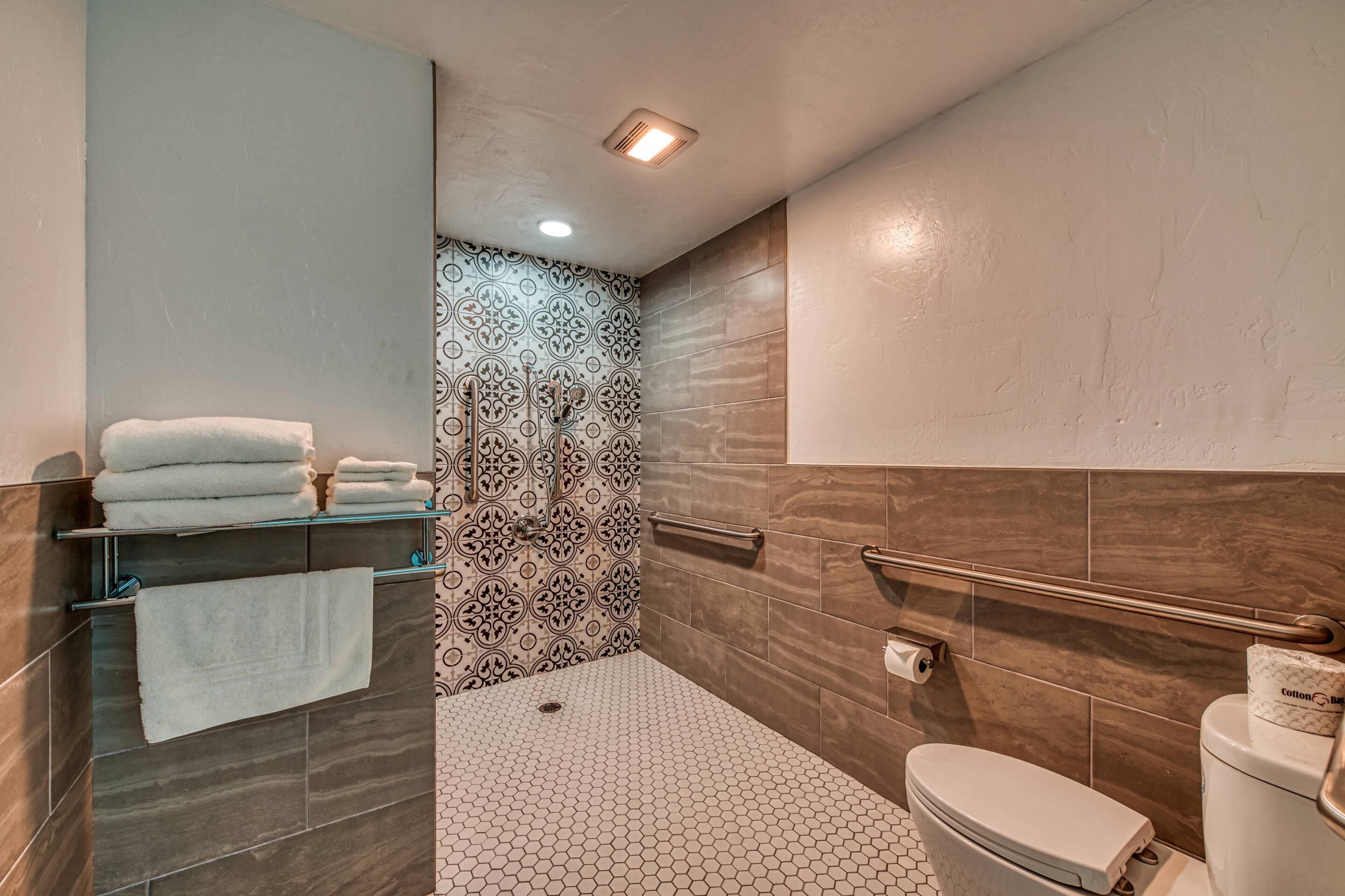 A modern bathroom with a shower, toilet, and towel rack.