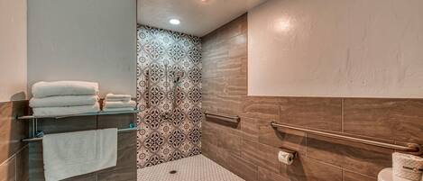 A modern bathroom with a shower, toilet, and towel rack.