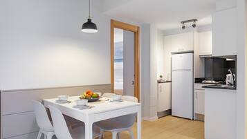 A modern kitchen with white cabinets, a black refrigerator, and a small island with a sink.