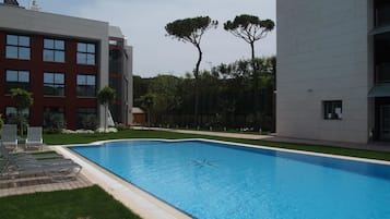 Un edificio moderno con piscina, rodeado de vegetación y árboles.