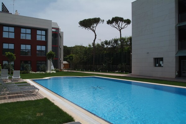 Un edificio moderno con piscina, rodeado de vegetación y árboles.