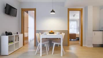 A modern, well-lit room with a dining table, chairs, a TV, and a bookshelf.