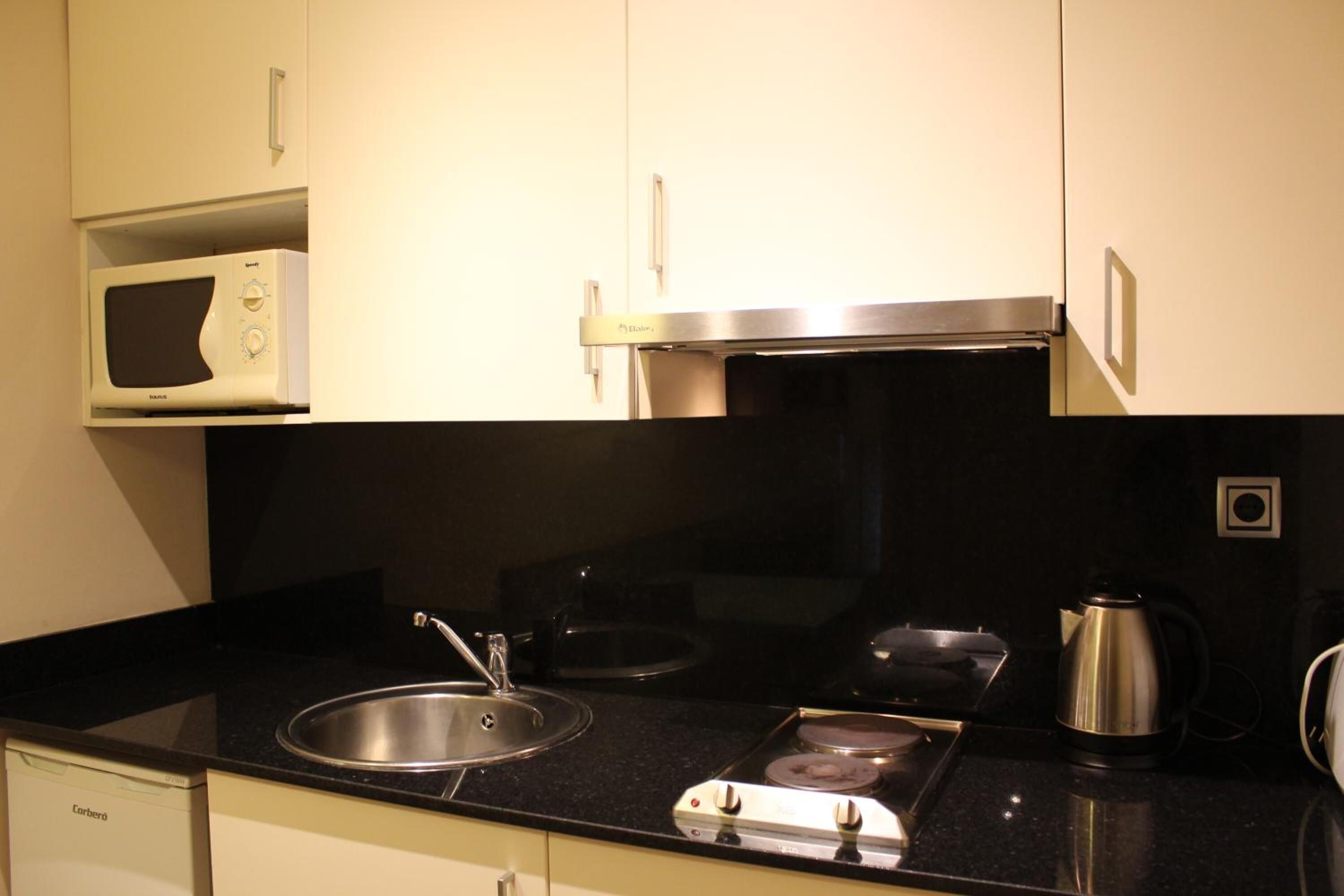 A kitchen with a microwave, stove, sink, and a coffee maker.