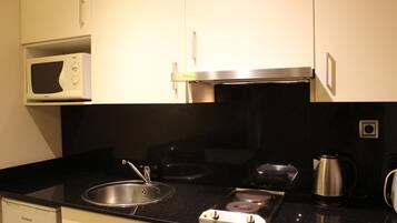 A kitchen with a microwave, stove, sink, and a coffee maker.