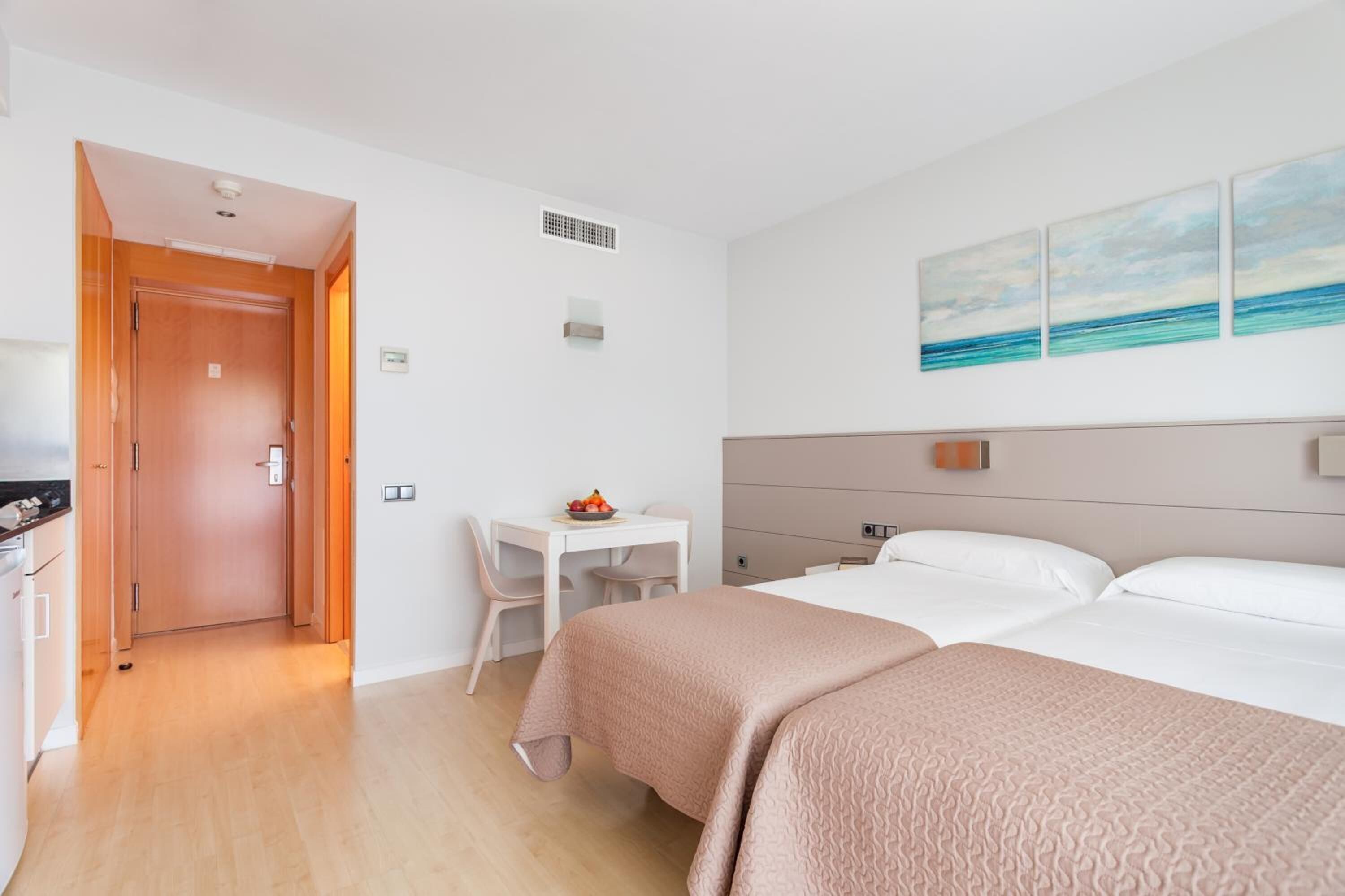 Ein Hotelzimmer mit zwei Betten, einem Schreibtisch und einem Stuhl.