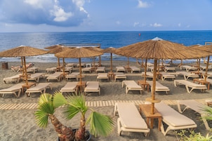 En la playa, sillas reclinables de playa, sombrillas, toallas de playa