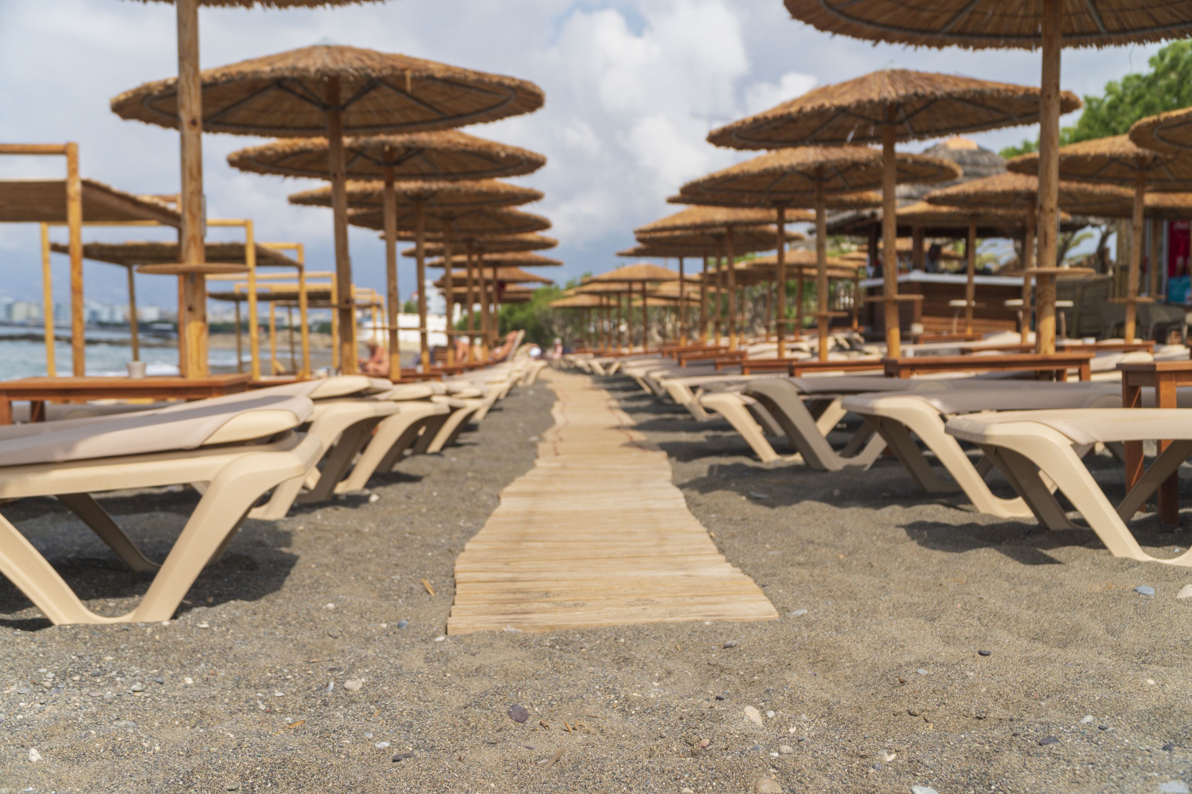 A beach with rows of sun loungers and thatched umbrellas.