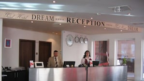 A reception desk at Grand Hotel Dream with a clock and a sign above it. - Grand Hotel Dream Frankfurt City (Frankfurt)