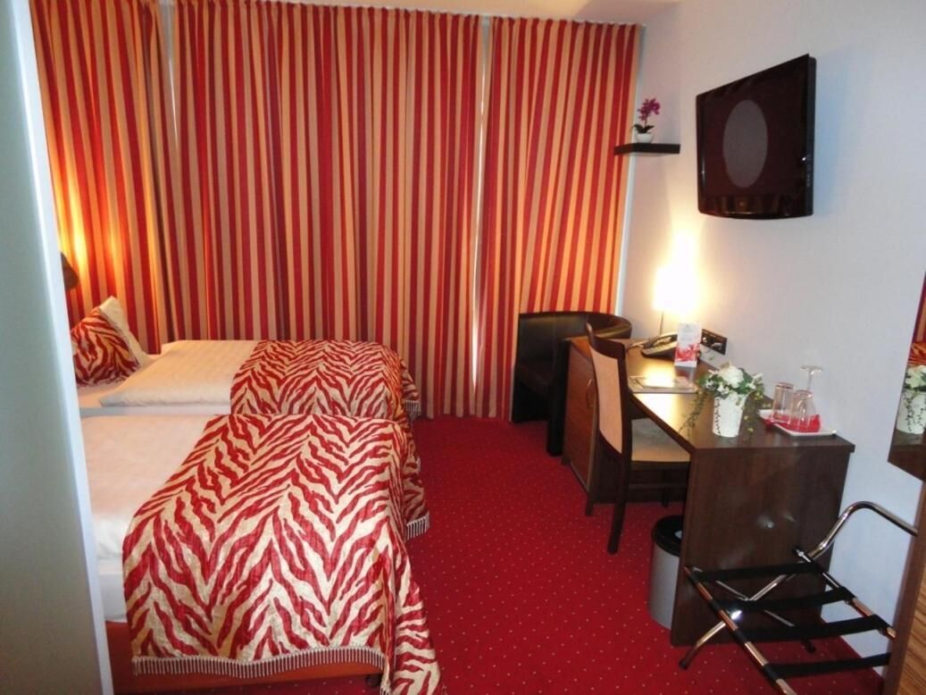 A hotel room with a bed, a desk, a chair, and a television.