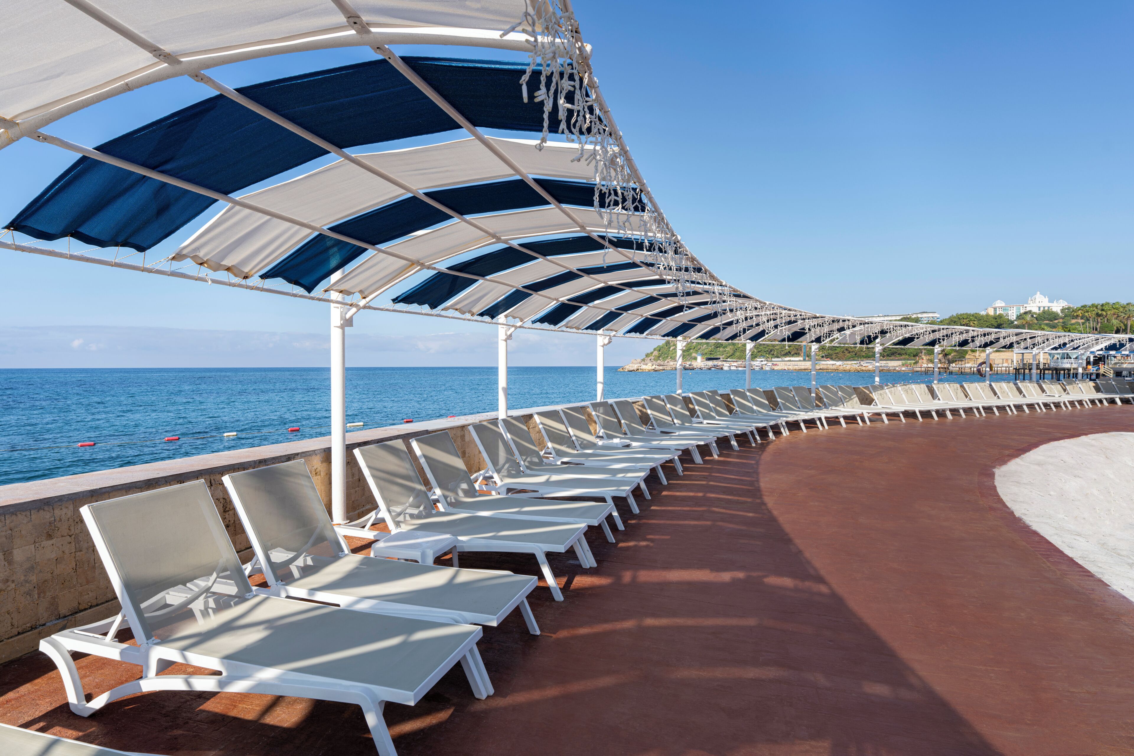 A sun deck with rows of white lounge chairs and a curved roof structure.
