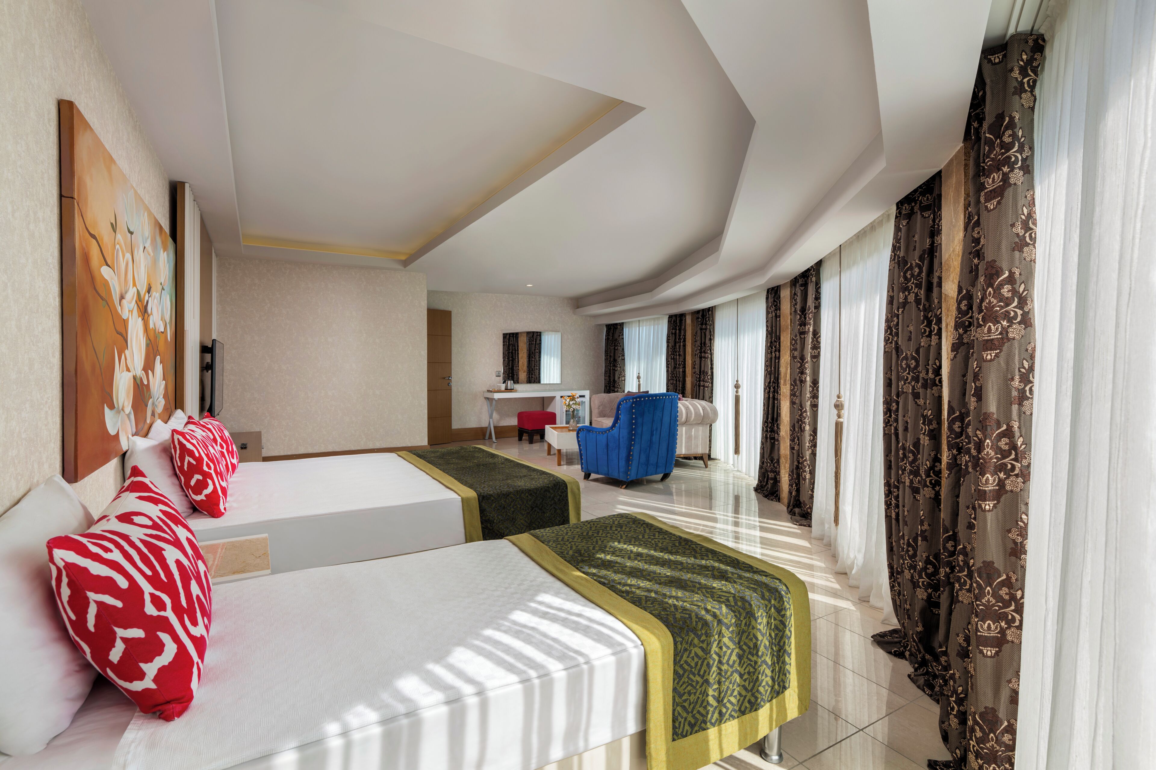 A hotel room with two beds, a desk, a chair, and a large window with curtains.