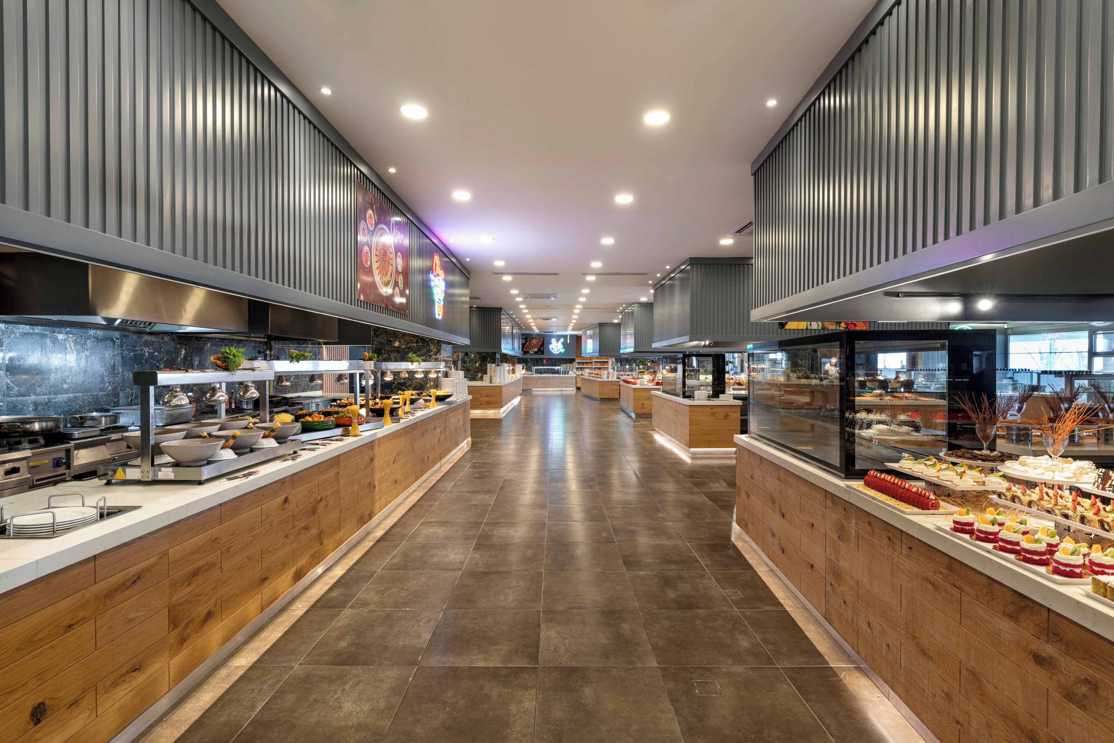 A modern buffet with a long counter, multiple food stations, and a central walkway.