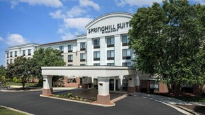 Un hotel llamado Springhill Suite by Marriott con un diseño arquitectónico moderno, que cuenta con una entrada cubierta y jardines ajardinados.