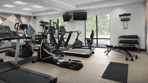 Un gimnasio moderno con cintas de correr, elípticas y pesas libres.