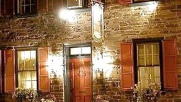 A two-story building with a wooden facade, multiple windows with shutters, and a central entrance with a door. - The Brafferton Inn (Gettysburg)