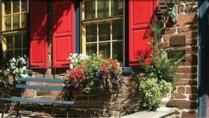 A stone building with red shutters and a bench in front. - The Brafferton Inn (Gettysburg)